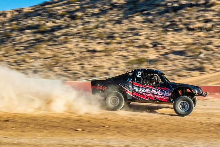 Dust kicks up as the baja race truck maneuvers through high-speed corners and exhilarating jumps offering an unforgettable ride through the rugged terrain just outside Las Vegas.